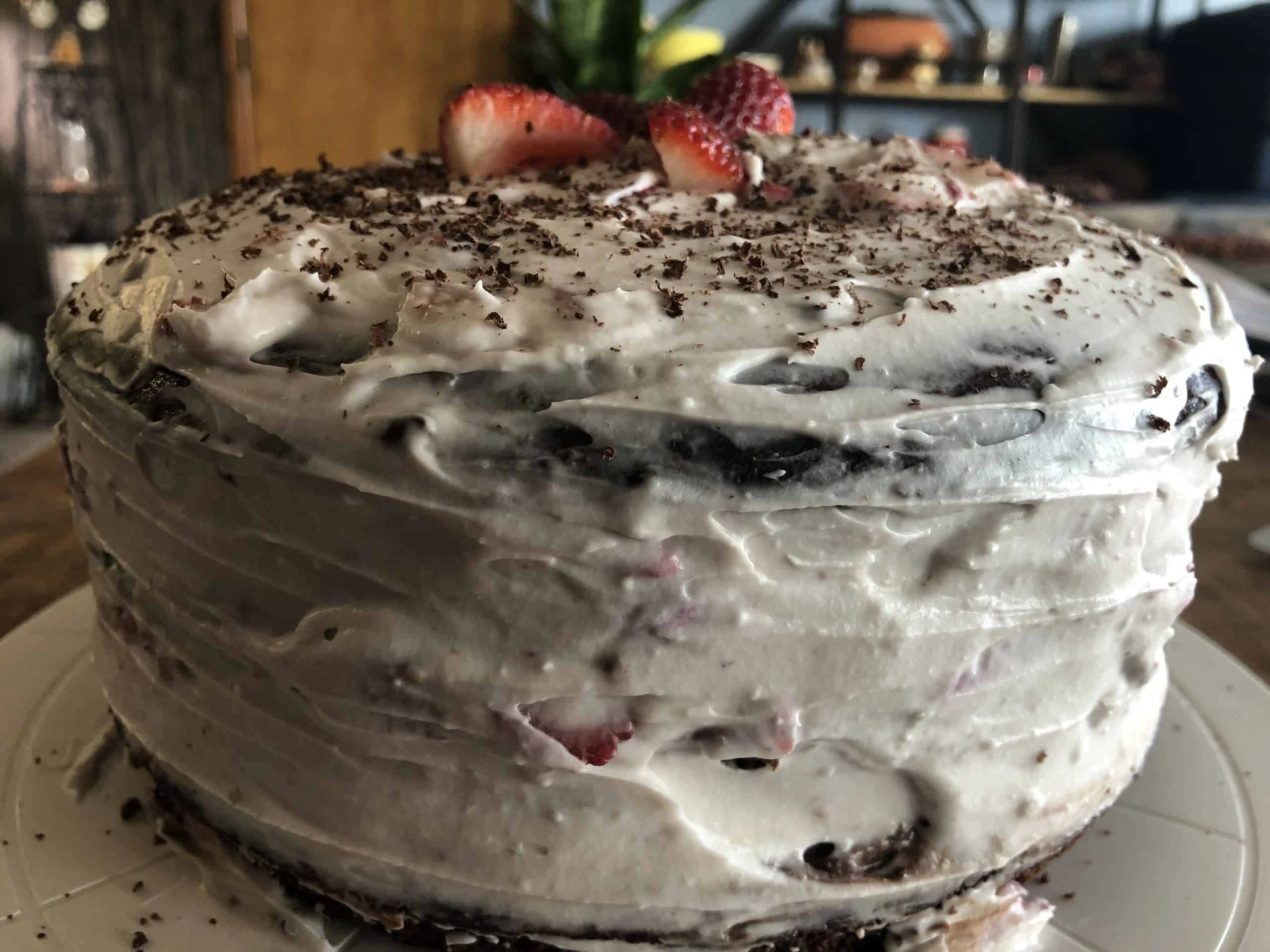 A layered cake with rich chocolate frosting and luscious strawberries on top.
