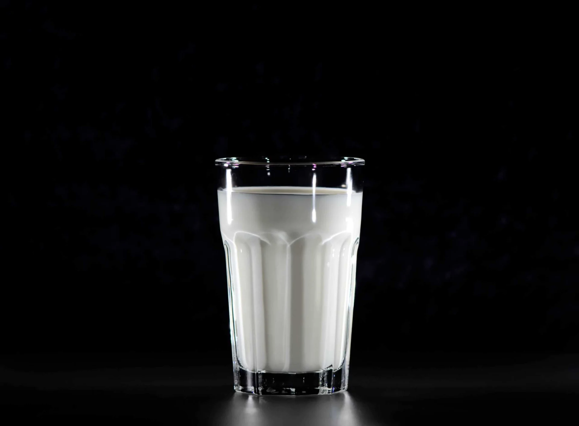A glass of milk on a black background.
