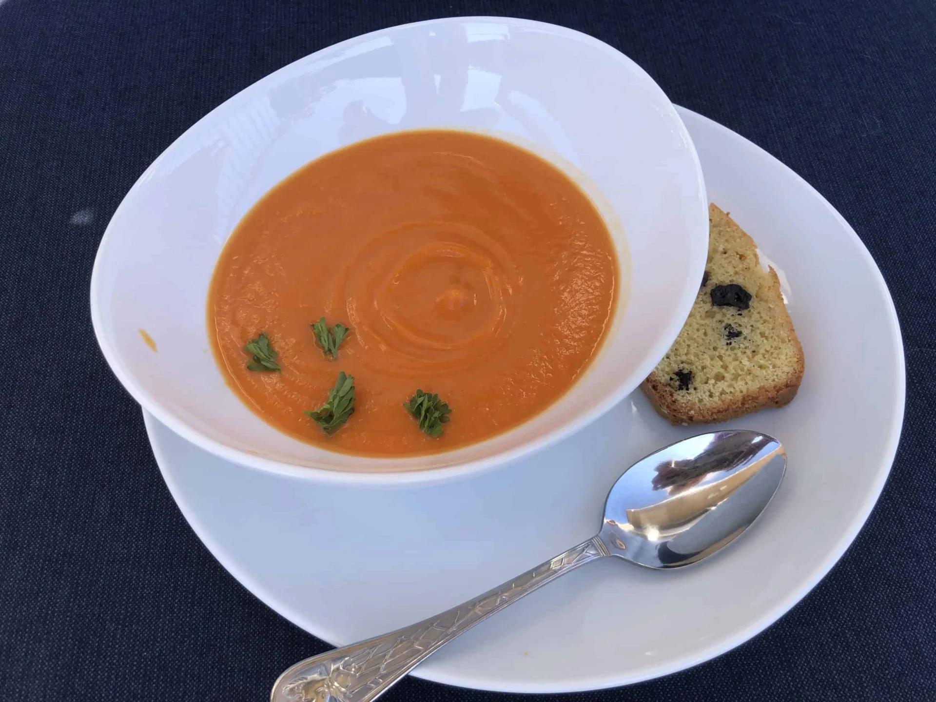 A bowl of tomato soup with bread and a spoon.